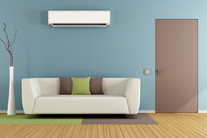 Image of a ductless system on a wall above a couch. Why Ductless Is the Way to Go.