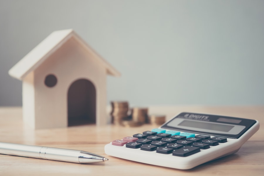 Calculator and a small wooden house sitting on a table.